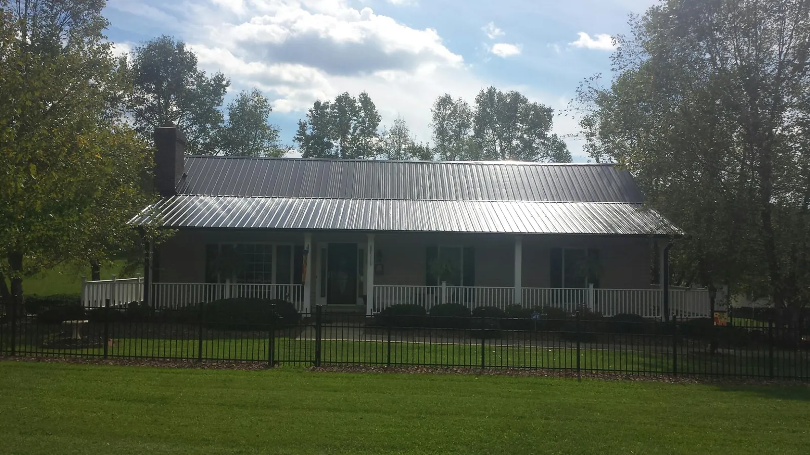 Gray metal roof on a brick ranch with a full width front porch — Gutter Guard Installation work by our crew in Davis